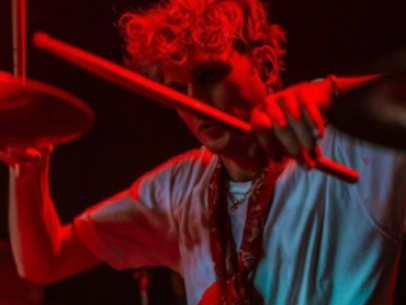 artista tocando bateria sob show de luzes vermelha enfrentando o desafio para artistas se destacarem