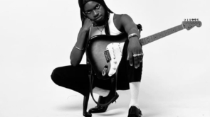 promovendo música de forma independente: artista com guitarra no colo sob fundo branco