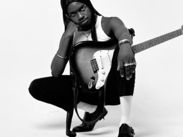 promovendo música de forma independente: artista com guitarra no colo sob fundo branco
